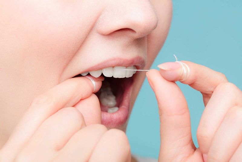 Bạn nên vệ sinh răng miệng bằng cách dùng chỉ nha khoa loại bỏ các mảng bám trên răng
