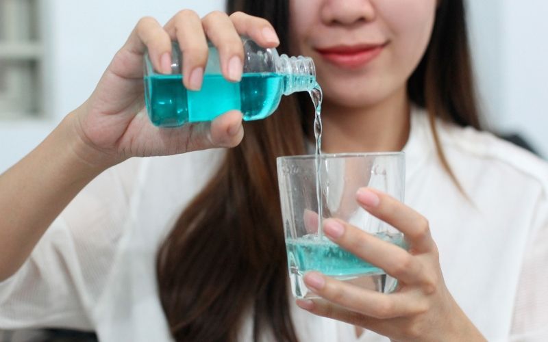 Bạn nên sử dụng nước súc miệng hoặc nước muối sinh lý để vệ sinh khoang miệng